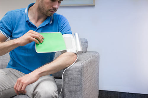 Scène de test de produit - Un homme utilise un tensiomètre futuriste (mesure de la pression artérielle)